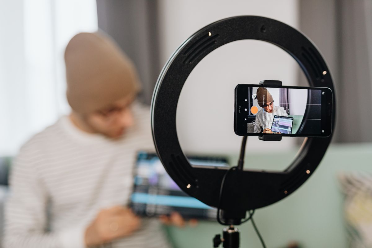 A creator filming himself on a phone mounted in front of a ring light